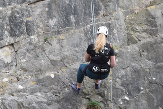 Girl abseiling down a vertical cliff