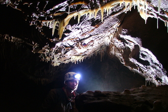 caver with head torch looking at stalagtites