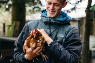 Young man holding a chicken at Future Roots Farm
