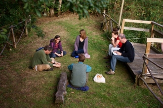 A group of people sitting on the grass relaxing at Magdalen Farm
