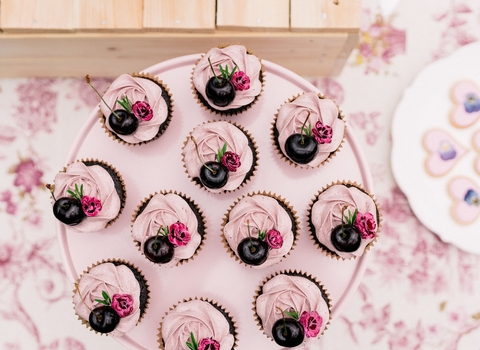 Beautiful pink cupcakes with cherries and pressed flowers