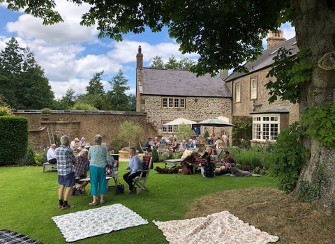 Guests enjoying tea and cake on the lawn