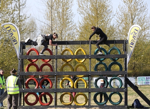 Two girls climbing over a wall of tyres