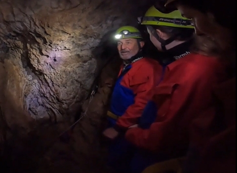 72 year old Steve kitted up to go caving for nature wearing overalls, head torch and helmet just inside the cave entrance