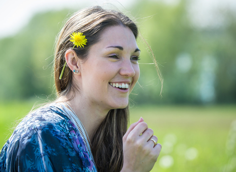 Woman smiling with a dandelion behind her ear