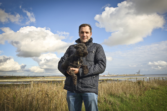 David holding his dog at a wetland