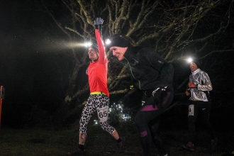 Happy night runners running through the trees with head torches