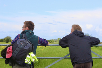 two people leaning over a gate
