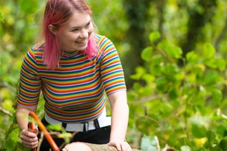 A young person working in the woodland in a bright striped t-shirt
