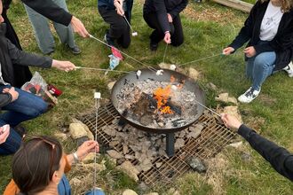 Image of Wilder Youth members toasting marshmallows over an open fire