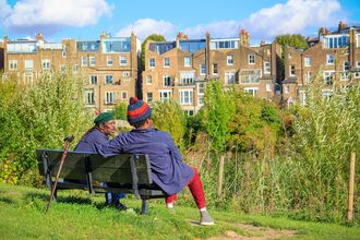 Two people sat on a bench in an urban park, talking