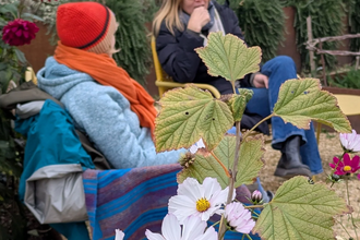 Women sharing honest conversation around a fire in a beautiful garden setting