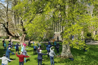 A group of people doing Tai Chi in the gardens at The Bishops Palace, Wells
