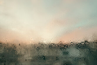 Condensation on a window with colours of pinks and blue penetrating through