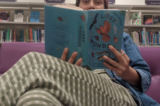 Kristen reading a book sitting in a chair at Taunton Library