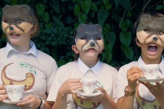 Three students wearing otter masks drinking tea from teacups and saucers