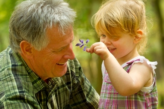 A young girl shows her grandad a bluebell 