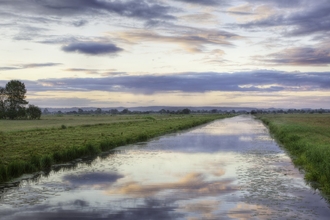 King's Sedgemoor Drain stretching through the flat Somerset Levels at sunrise.