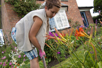 Gardening with wildlife, woman digging with house and garden in background
