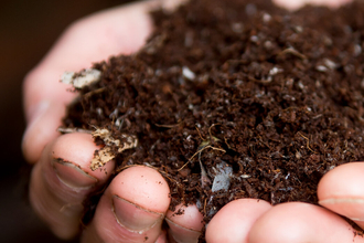 A close up photo of a person's hands holding two handfuls of soil