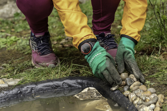 A person adding pebbles to the edge of a new garden pond