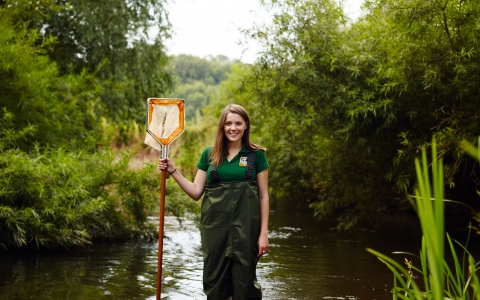 Sophie standing in a river with a net