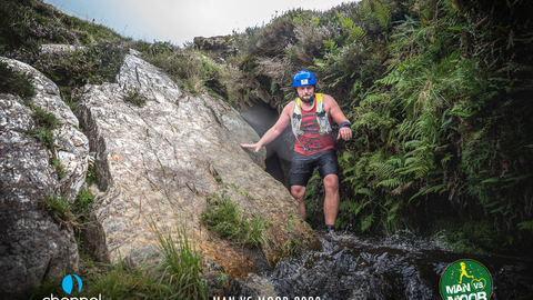 Man in helmet climbing out of a cave in Exmoor National Park