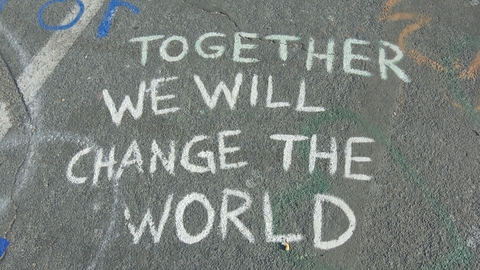 Chalk writing on street. "Together we will change the world."
