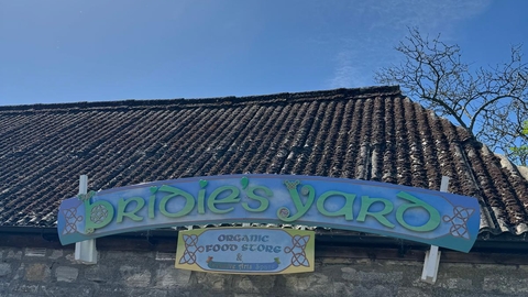 A sign on the side of a old grey brick barn reads 'Bridie's Yard'