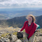 Jemima Western, Peatland Partnership Farm Liaison Officer at Somerset Wildlife Trust, smiling at camera, with views of hills in background