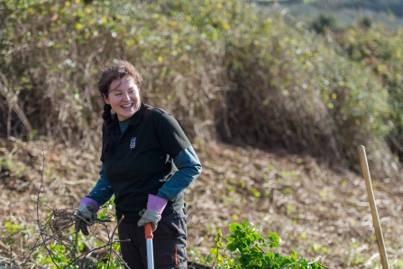 Young woman laughs as she helps carry out reserve management work