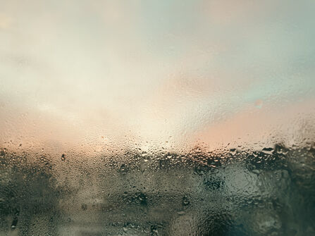 Condensation on a window with colours of pinks and blue penetrating through
