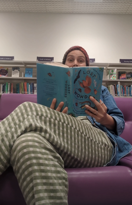Kristen reading a book sitting in a chair at Taunton Library