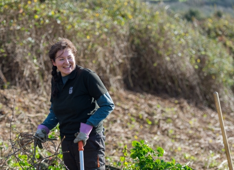 Young woman laughs as she helps carry out reserve management work