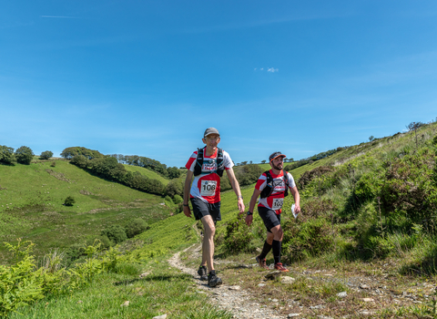 2 men hiking through the rolling hills of the Exmoor National Park with clear blue skies