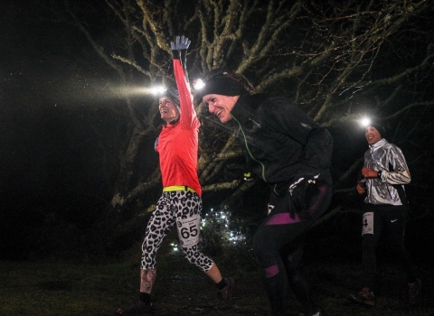 Happy night runners running through the trees with head torches