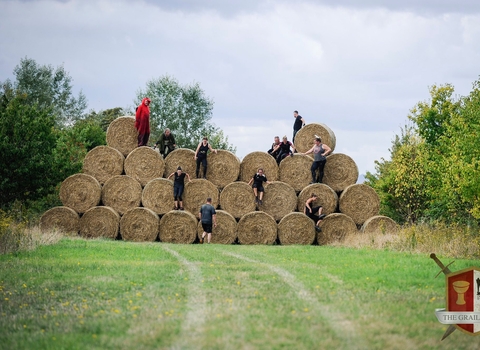 Participants scaling a huge wall of hay bales