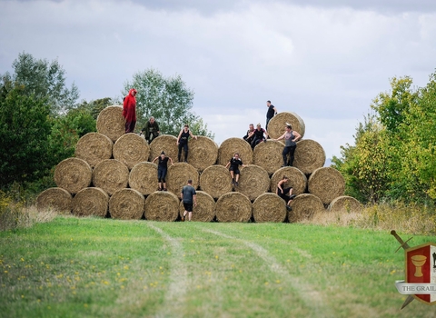 Participants scaling a huge wall of hay bales