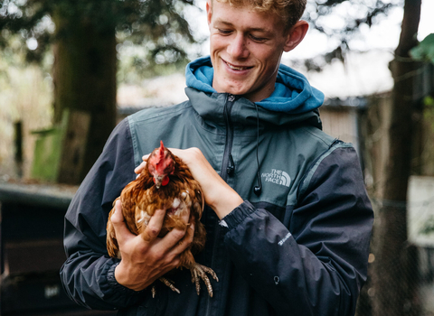 Young man holding a chicken at Future Roots Farm