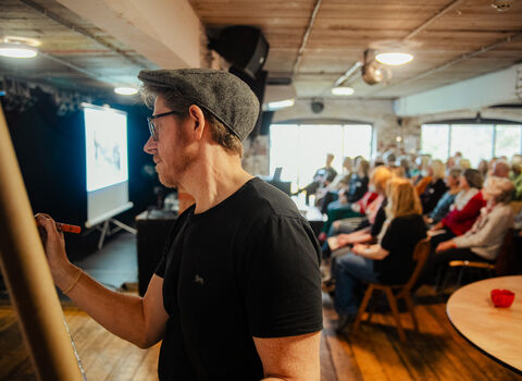 A man live illustrates a meeting full of people