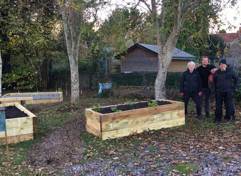 People stand next to raised beds they have built