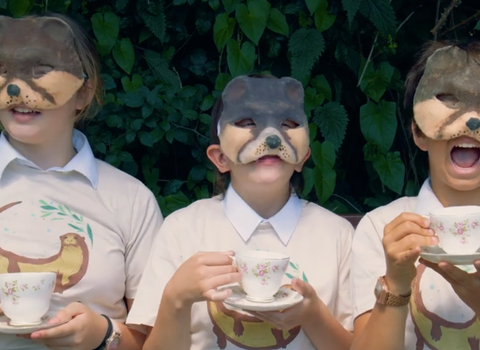 Three students wearing otter masks drinking tea from teacups and saucers
