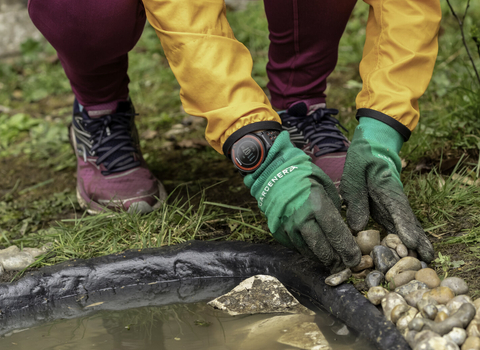 A person adding pebbles to the edge of a new garden pond